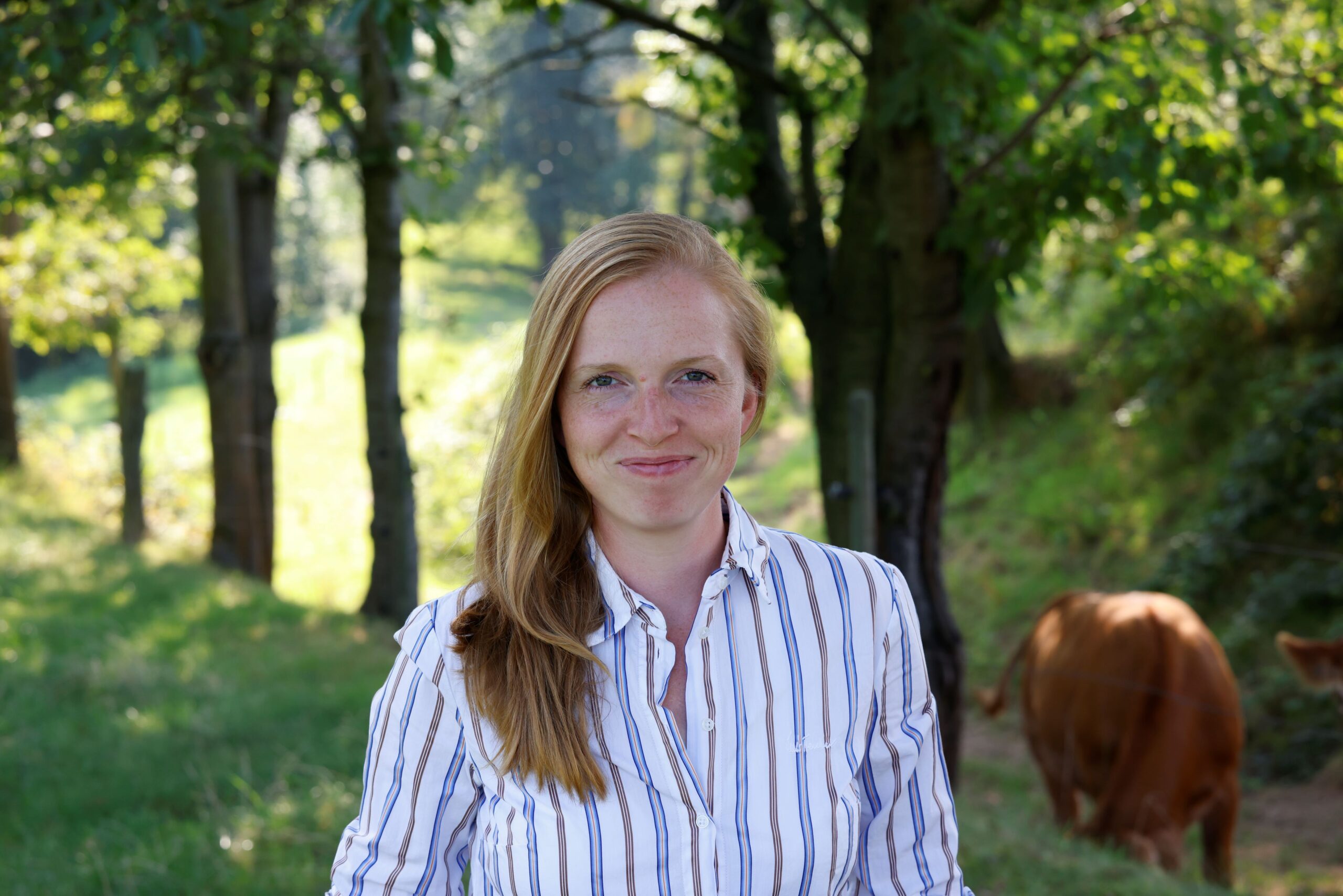 Coachin freut sich vor Bäumen und Kühen auf ihr Team Entscheidern zur Bewältigung von Veränderungsprozessen