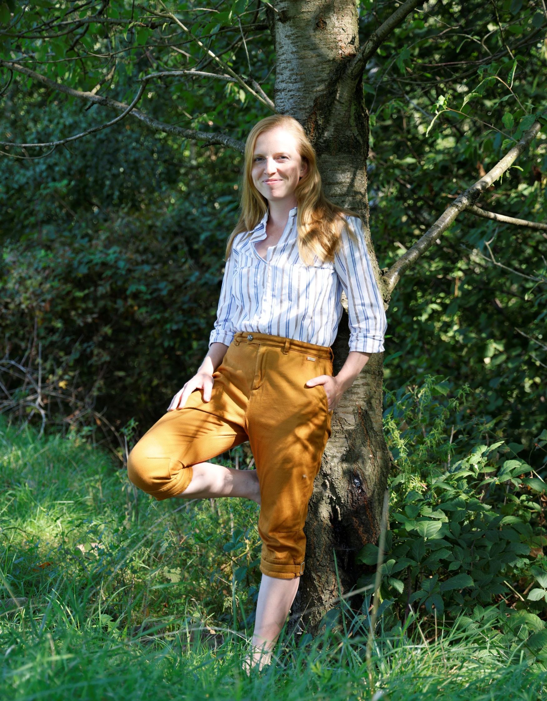 Coachin Kristin Klengel in der Natur fernab vom Alltag an einen Baum gelehnt und bereit für Führungskräfte in Veränderungsphasen